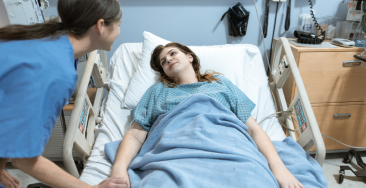 Patient lying in a hospital bed looking at a nurse.