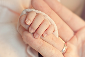 A person holding a new born baby hand