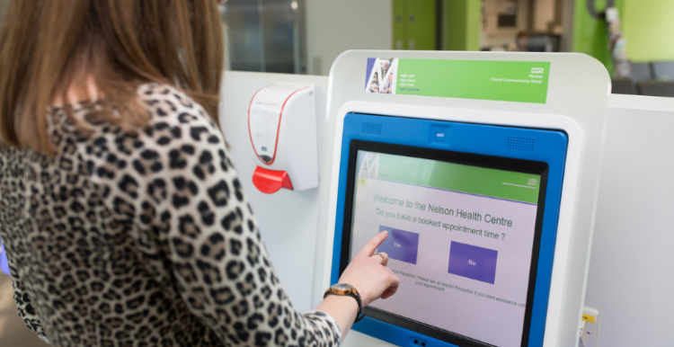 Image of a lady pressing buttons on a registration machine.