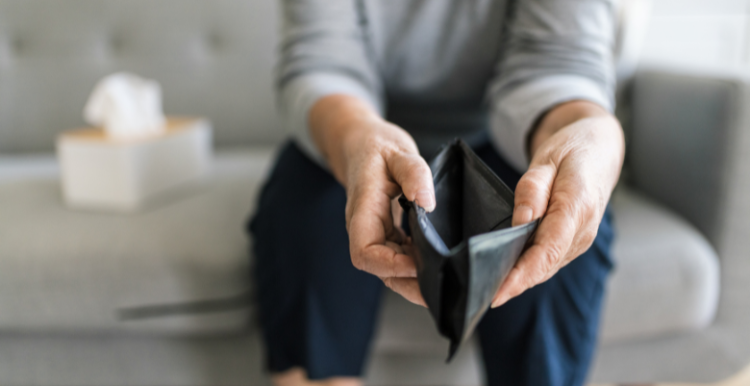 Person sat on a sofa holding out an empty wallet