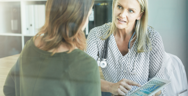 Image of a doctor talking to a patient and looking at a tablet screen