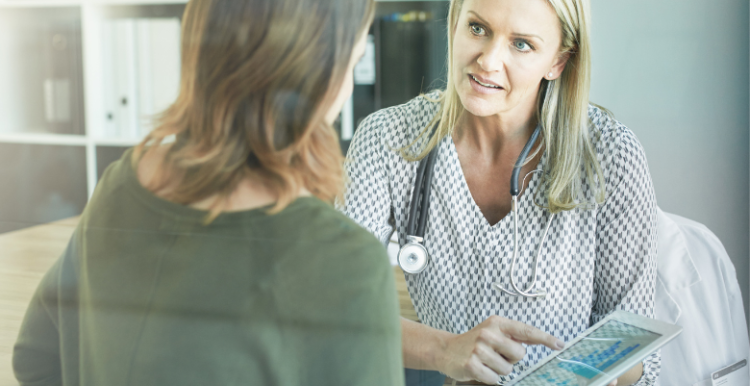 Image of a doctor talking to a patient and looking at a tablet screen 