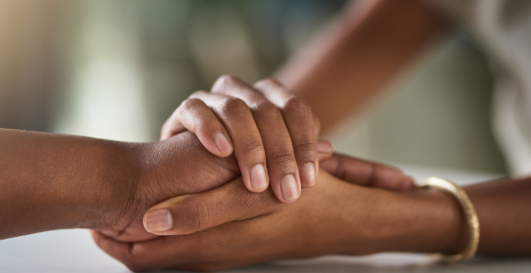Two people holding hands for support