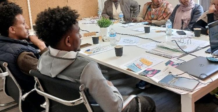 A group of people sat together in a room listening to a presentation about Healthwatch