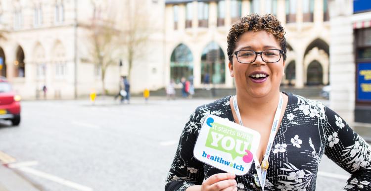 Healthwatch staff member holding an It Starts With You sign to promote giving views Healthwatch staff member holds an It Starts With You sign to promote giving views