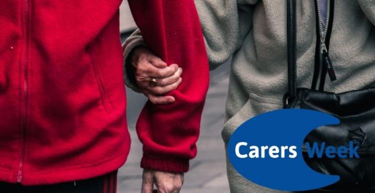 Image shows two elderly people walking together. The woman is holding the man's arm. The Carers Week logo is in the corner.