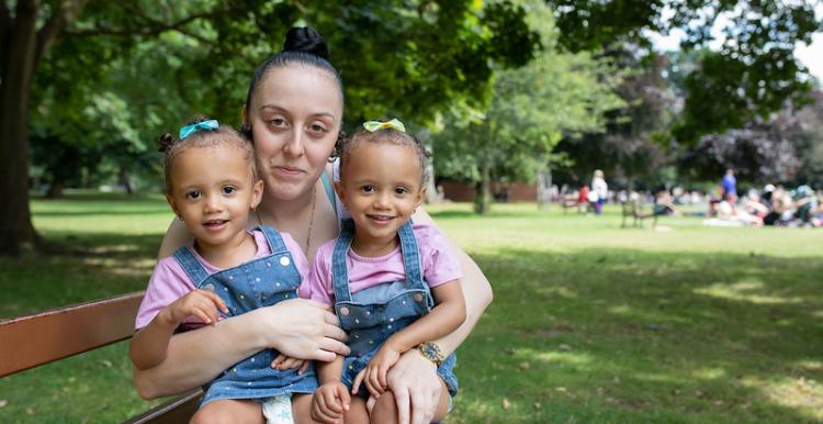 A woman sat on a bench with her two young children