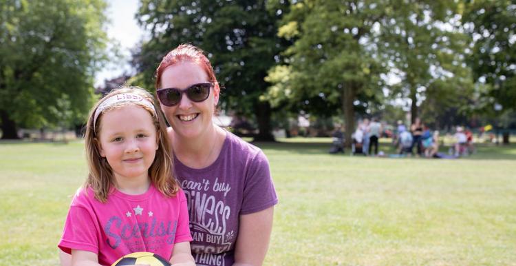 Women and young daughter sitting down at the park