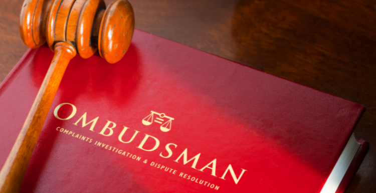 Image of a wooden gavel resting on a red book entitled "Ombudsman".