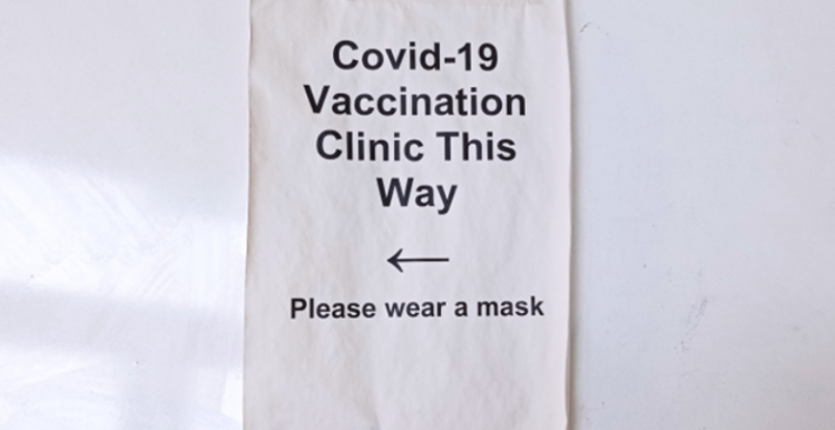 A sign pointing to a covid vaccination clinic A paper sign with arrow which reads