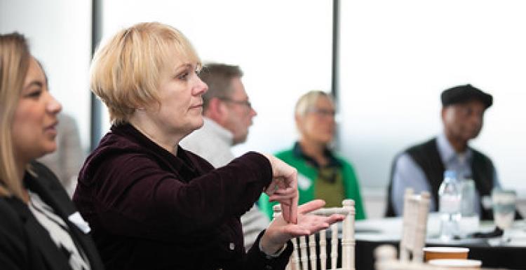 A group of people seated, one of them using sign language