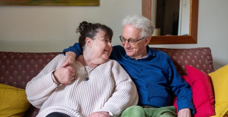 Two older people sitting on a sofa.