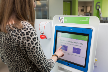 Image of a lady pressing buttons on a registration machine.