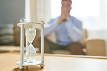 Man sitting on a sofa watching a sand timer