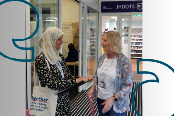 Two women standing talking in entrance to NHS building