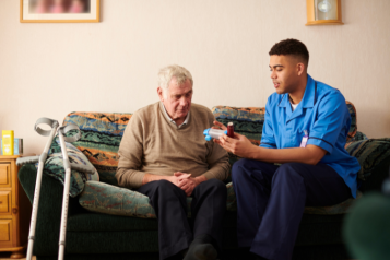 An elderly man receiving medication from a nurse