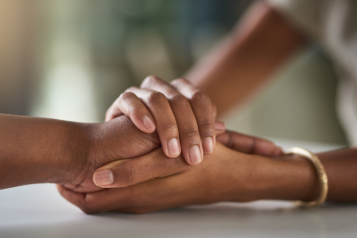 Two people holding hands for support