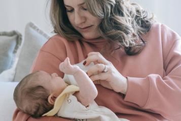 A lady feeding her baby with a bottle