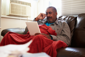 A man siting on the sofa reading information from a leaflet