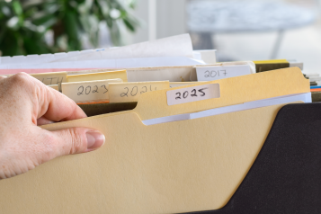 A person's hand grabbing a paper file