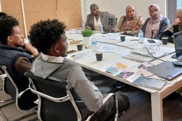 A group of people sat together in a room listening to a presentation about Healthwatch