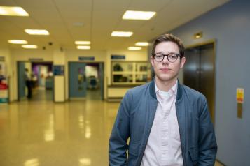 Young man standing face on to camera in a hospital hallway