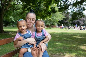 A woman sat on a bench with her two young children