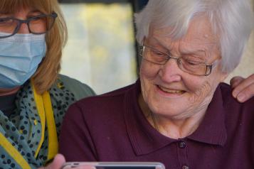 Elderly lady looking at phone with family member