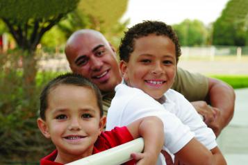 Man smiling with his two young children