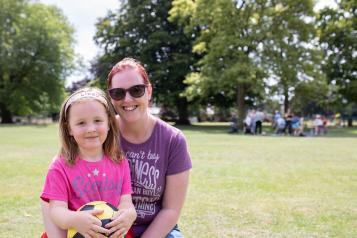 Women and young daughter sitting down at the park