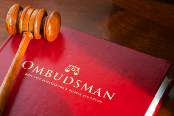 Image of a wooden gavel resting on a red book entitled "Ombudsman".