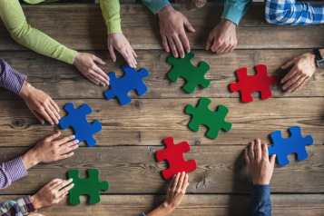 People sat round a table with giant jigsaw pieces