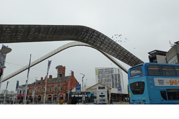 Coventry's whittle arch with people and buses passing by
