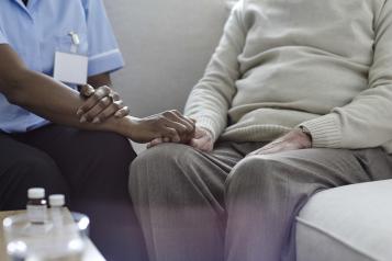 A nurse holding an older man's hand