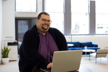 Smiling man seated and using a laptop 