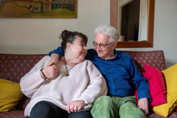 Two older people sitting on a sofa.