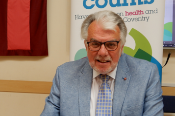 Picture of Stuart Linnell sitting at a meeting table and smiling