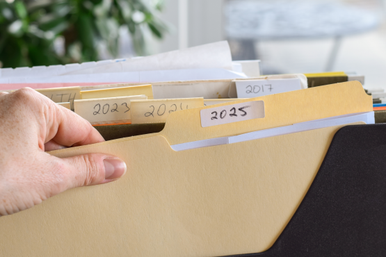 A person's hand grabbing a paper file