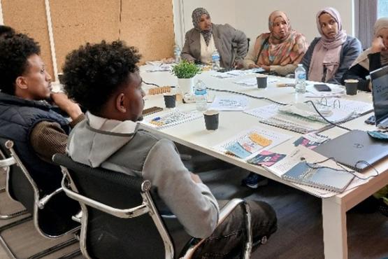 A group of people sat together in a room listening to a presentation about Healthwatch