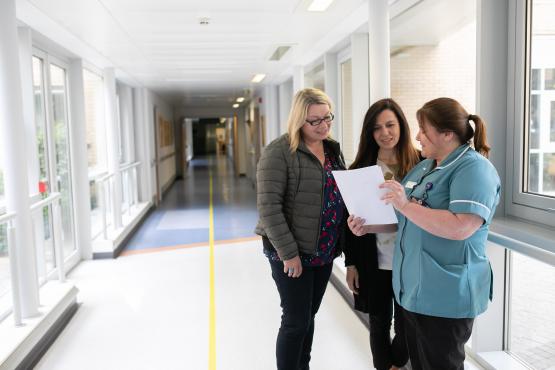 Two volunteers on hospital visit talking to nurse Two olunteers on hospital visit talking to nurse