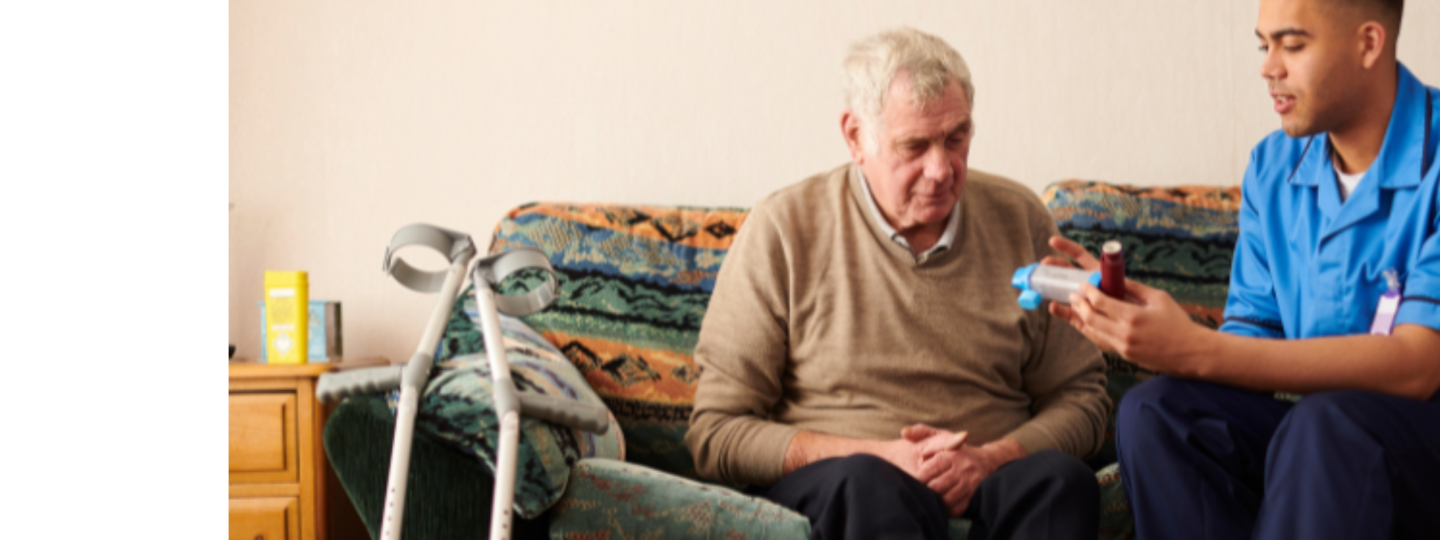 Elderly man receiving medication from a carer