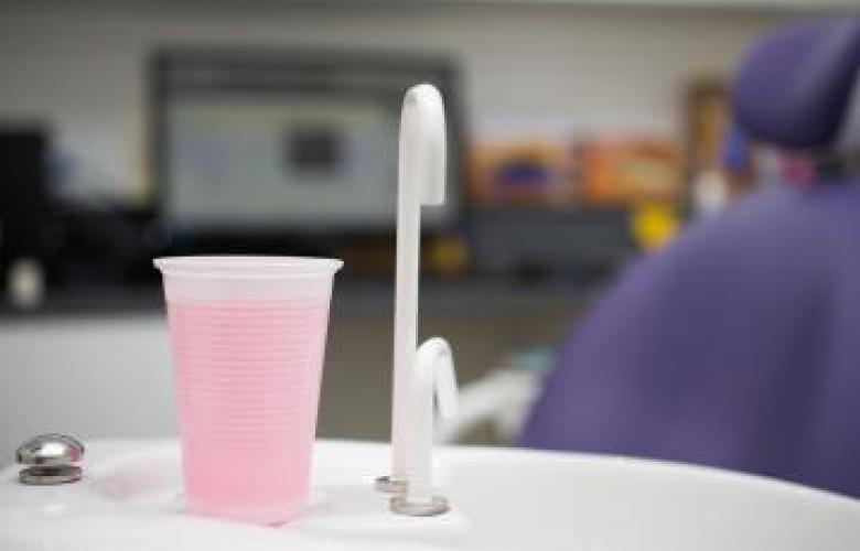 A cup of pink liquid and a tap in a dentist's room