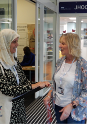 Two women standing talking in entrance to NHS building