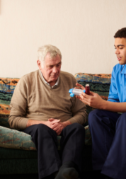 Elderly man receiving medication from a carer